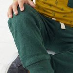 Person wearing green pants and a yellow top with a white background