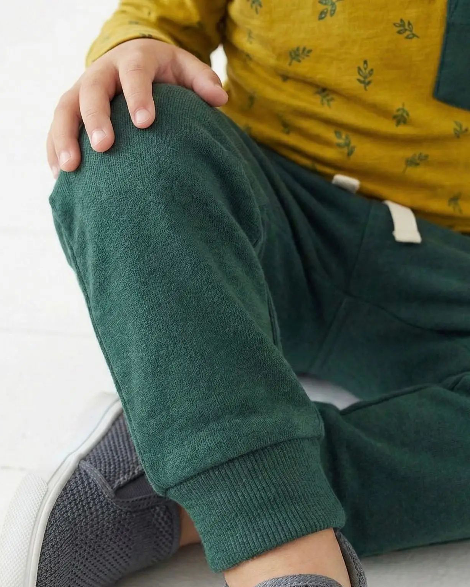 Person wearing green pants and a yellow top with a white background