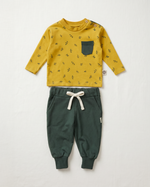 Yellow long-sleeve shirt with black pattern and green pants on a white background