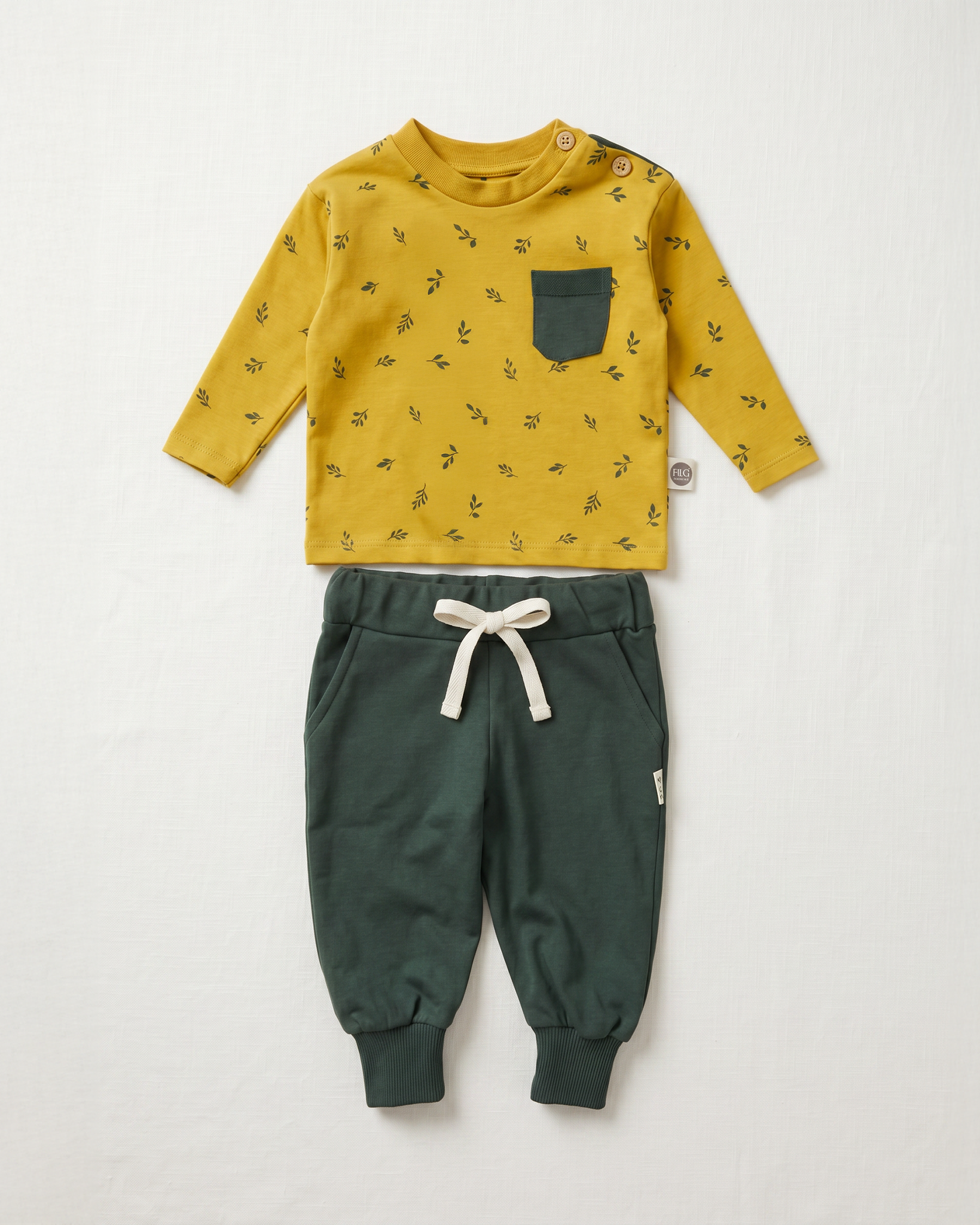 Yellow long-sleeve shirt with black pattern and green pants on a white background