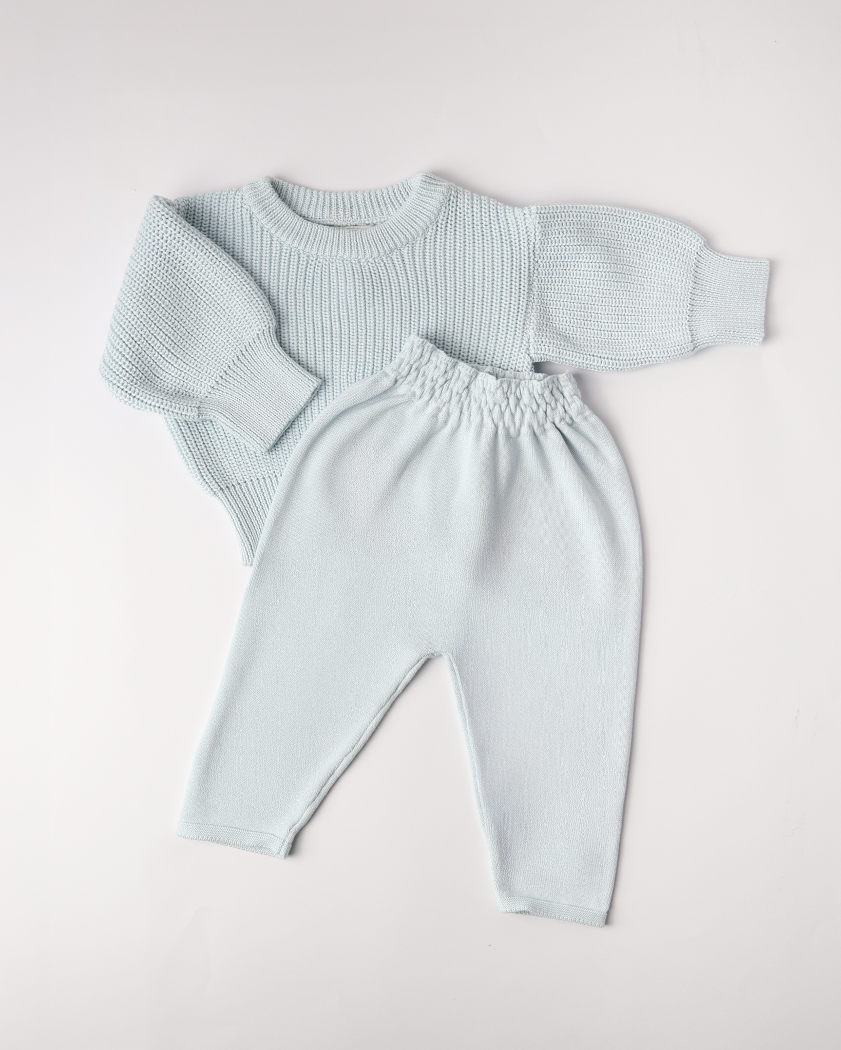 Light blue knitted sweater and pants set on a white background