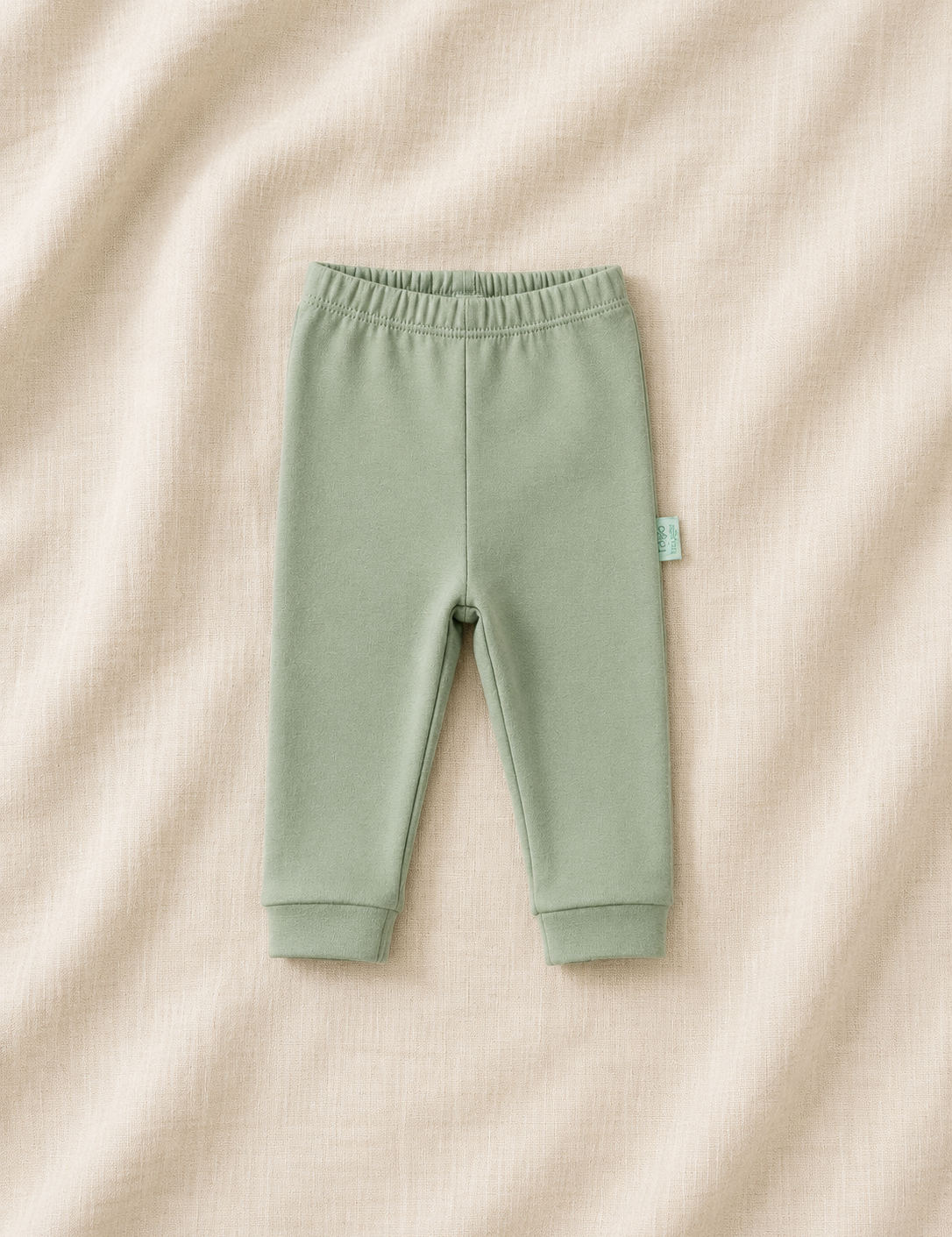 Green baby pants on a beige fabric background
