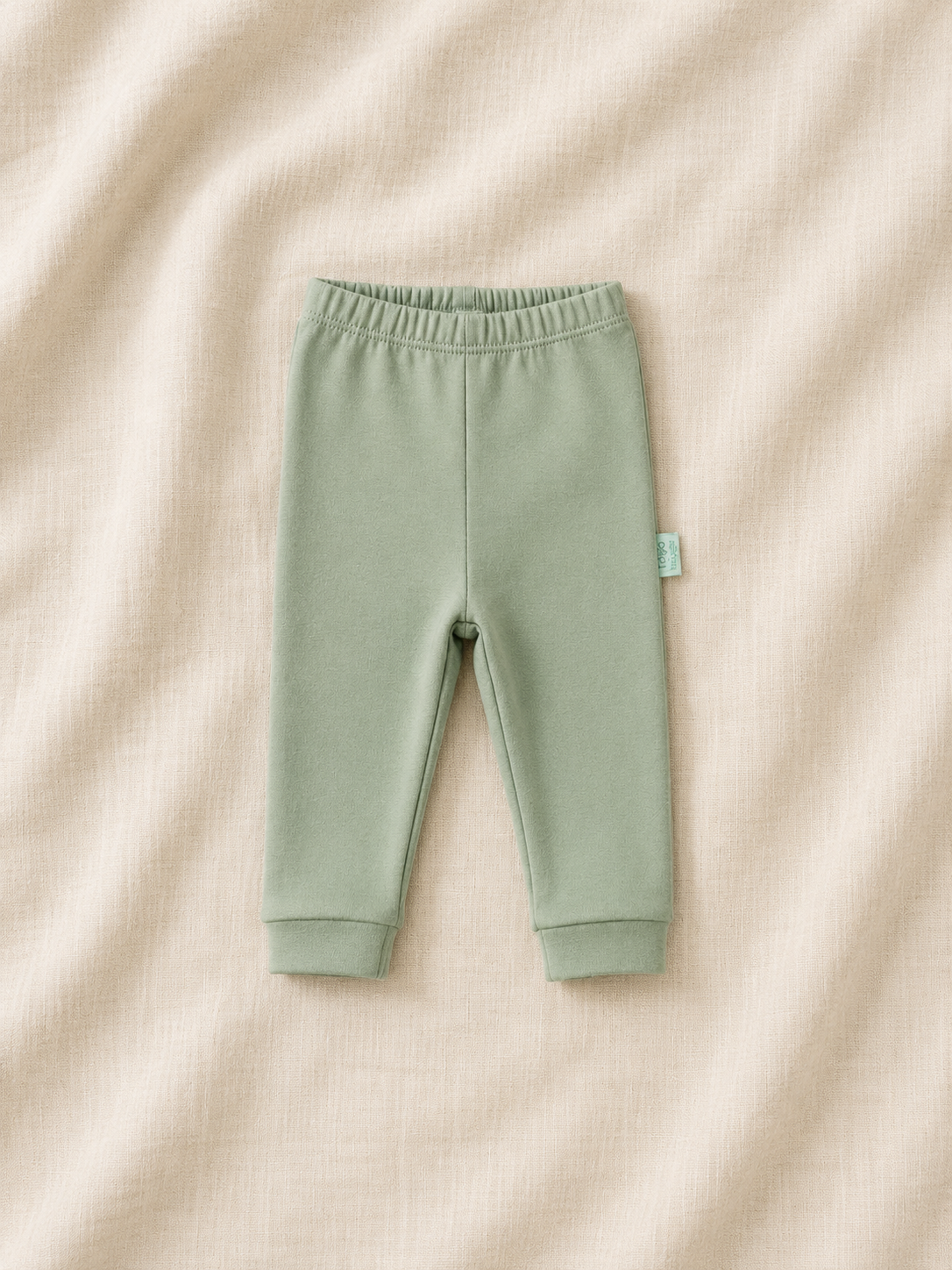 Green baby pants on a beige fabric background